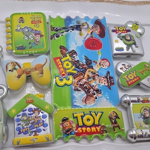 Puede incluir: Una colecci&oacute;n de imanes y amuletos con el tema de Toy Story. Los dise&ntilde;os presentan personajes como Buzz Lightyear, Woody y otros de la serie de pel&iacute;culas animadas. Los art&iacute;culos tienen varias formas, incluyendo una mochila, casas y libros.