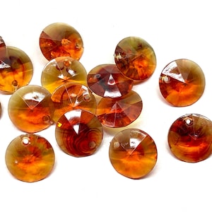 May include: A collection of amber-colored, faceted, round glass beads with a hole in the center. The beads have a shiny, iridescent finish.