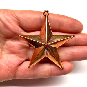 May include: A large, copper-colored, five-pointed star ornament with a loop at the top for hanging.