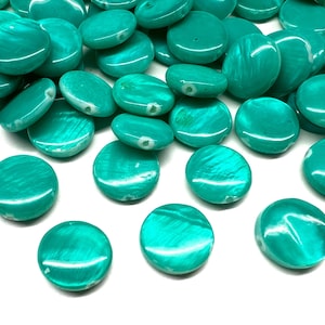 May include: A collection of round, flat, turquoise-colored beads with a pearlescent, shimmering finish. Each bead features a smooth, circular shape with a visible center hole for threading, displaying a consistent vibrant teal hue.