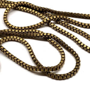 May include: A gold-toned chain necklace with a box chain design. The chain is made of small, square links.