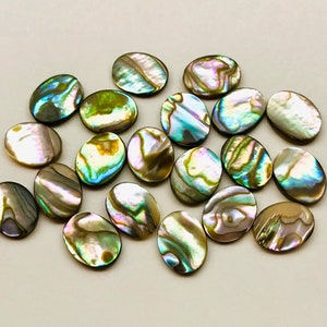 May include: A collection of oval-shaped abalone shell cabochons in shades of green, blue, and gold. The shells have a natural iridescent sheen.