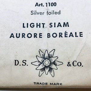 以下が含まれることがあります： 「Art. 1100 Silver foiled LIGHT SIAM AURORE BOR&Eacute;ALE」と黒文字で書かれた白いラベルと、中央にダイヤモンドがついた花の白黒イラスト。ラベルには「D.S. & Co. TRADE MARK」の文字も印刷されている。