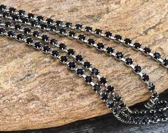 May include: Black rhinestone chain trim with silver metal connectors. The chain is made of small, square-shaped rhinestones.