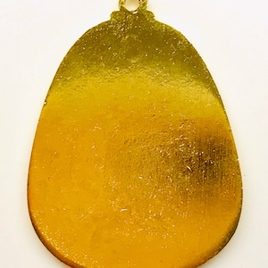 May include: A gold-colored metal ornament shaped like an egg with a small loop at the top.