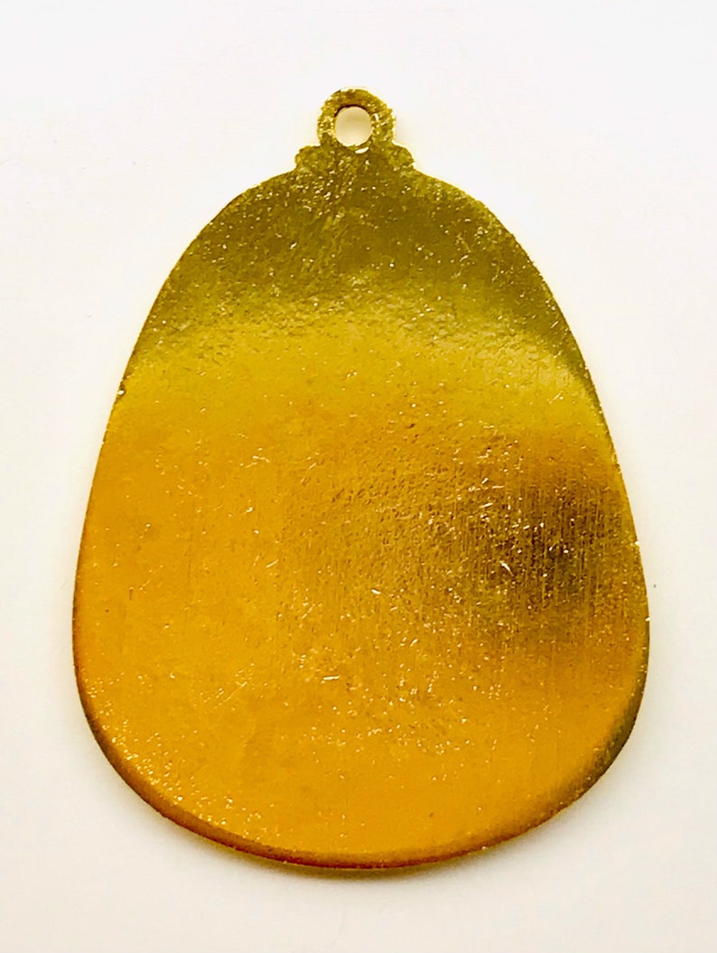 May include: A gold-colored metal ornament shaped like an egg with a small loop at the top.