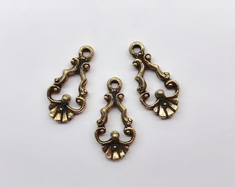 May include: Three antique brass-toned metal charms featuring an openwork teardrop shape with intricate scrollwork, a small circular loop at the top for attachment, and a fan-shaped base detail with a central raised bead on each individual piece.
