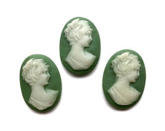May include: Three green cameo pendants with white raised profile images of women. The women are facing to the right and have their hair pulled back.
