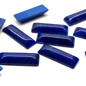 May include: A group of twelve rectangular lapis lazuli cabochons, each with a smooth, polished surface and a deep blue color.