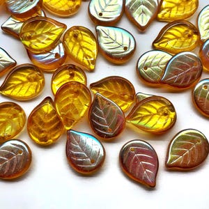 May include: A collection of iridescent leaf-shaped beads in shades of gold, amber, and silver. Each bead features a detailed leaf vein design and a small hole for stringing. These decorative beads are ideal for jewelry making and craft projects.