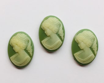 May include: Three oval-shaped green cameo pendants with a white cameo image of a woman's profile.