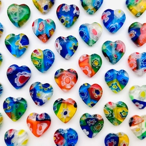 May include: A collection of colorful heart-shaped glass beads with intricate patterns. The beads are arranged in a grid pattern on a white background.