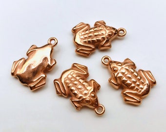 May include: Four copper frog charms with a detailed design. The frogs are in various poses and have a shiny finish.