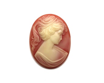 May include: A cameo featuring a woman's profile in white against a red background. The woman has her hair pulled back and is wearing a simple garment.