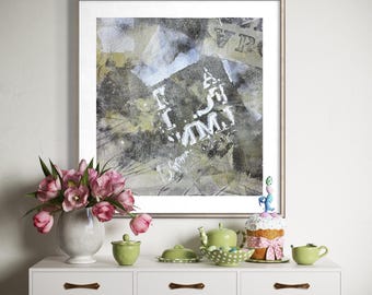 May include: A framed abstract print with gray, white, and olive tones hangs above a white console table. The table holds a ceramic vase with pink tulips, a small green lidded jar, a green teapot, a bowl of green candies, and a cake.