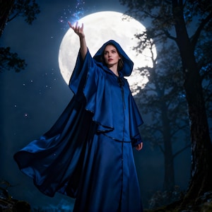 May include: A person wearing a long, flowing, dark blue hooded cloak and dress, set against a backdrop of a full moon and a forest. The person's hand is raised, with glowing blue light emanating from it.