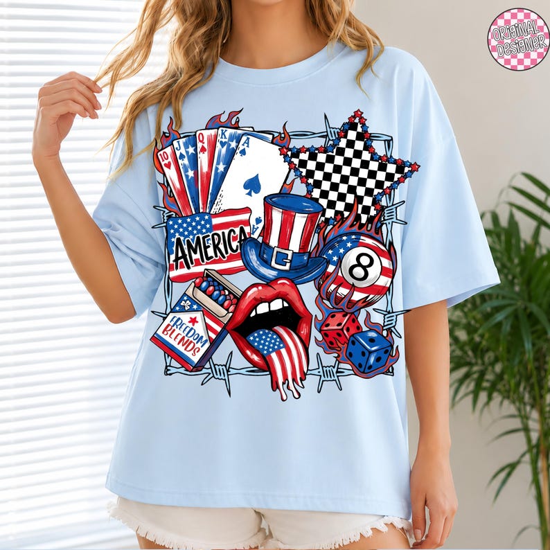 May include: Light blue t-shirt with a graphic design featuring patriotic symbols. The design includes playing cards, an American flag, a top hat, a star, dice, and the word "AMERICA". The shirt also has the text "FREEDOM BLENDS".
