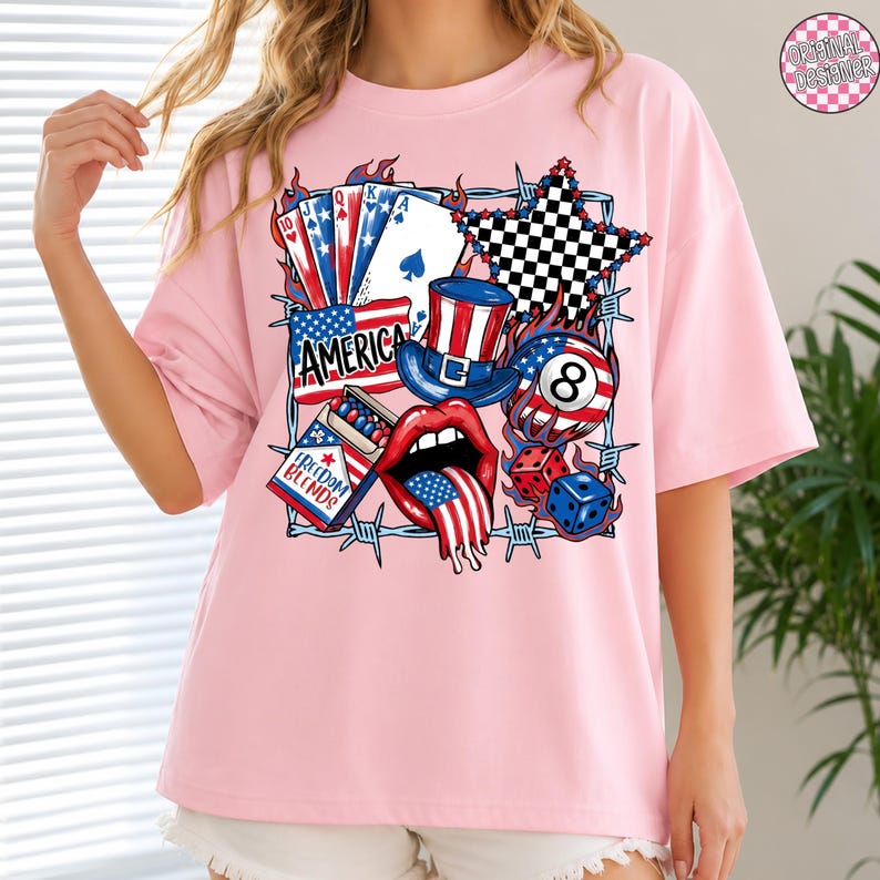 May include: Pink t-shirt with a patriotic graphic featuring playing cards, a star, a top hat, an eight ball, dice, and a mouth with a tongue shaped like the American flag. The word "AMERICA" is also displayed.