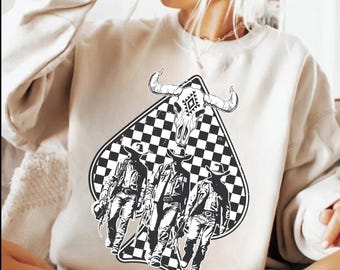 Könnte beinhalten: Cremefarbenes Sweatshirt mit einer schwarz-weißen Grafik. Die Grafik zeigt eine rautenförmige Form mit Schachbrettmuster, einen Bullenschädel und drei Figuren in Cowboy-Kleidung. Das Design ist auf der Vorderseite des Sweatshirts zentriert.