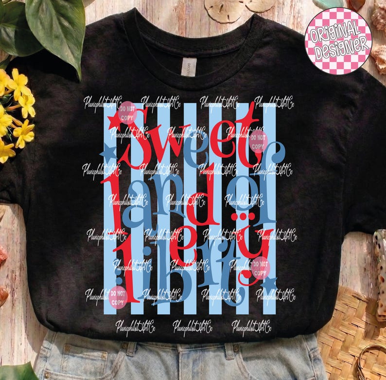 Puede incluir: Camiseta negra con un dise&ntilde;o patri&oacute;tico. La camiseta presenta las palabras "Sweet Land of Liberty" en rojo y azul, con rayas azules y blancas. Un peque&ntilde;o logotipo de "Original Designer" est&aacute; en la esquina superior derecha.