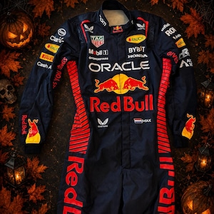 Op de afbeelding: Een donkerblauw racepak met opvallende rode en gele Red Bull-branding, inclusief Oracle, Honda en Tag Heuer-logo's. Het pak heeft rode zijpanelen met gestreepte details, lange mouwen en de tekst MAX met een Nederlands vlagicoon.
