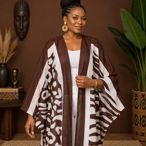 Peut inclure: Un kimono ouvert marron et blanc avec un motif animalier mélangé. Le vêtement présente un panneau vertical marron uni le long de l'ouverture avant, des manches larges et une silhouette ample et fluide qui se porte sur un haut et un pantalon blancs.