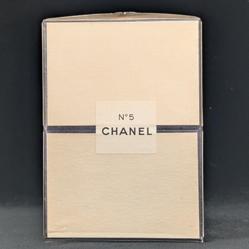 Pu&ograve; includere: Scatola rettangolare color crema con etichetta bianca con la scritta "N&deg;5 CHANEL". Il bordo della scatola &egrave; blu scuro.