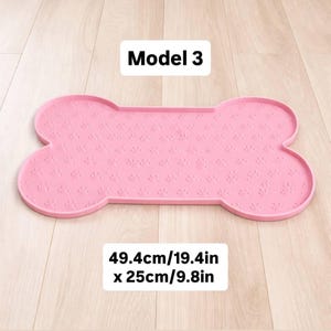 May include: Pink bone-shaped pet food mat with paw print pattern. The mat measures 19.4 inches long and 9.8 inches wide. The text "Model 3" is at the top.