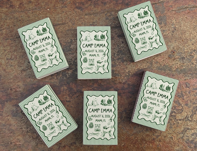 Op de afbeelding: Vijf kleine, rechthoekige notitieboekjes met een groen-witte gestreepte rand. Elk notitieboekje bevat de tekst "CAMP EMMA AUGUST 14, 2026 MIAMI, FL" in een decoratief kader met kampeerillustraties.