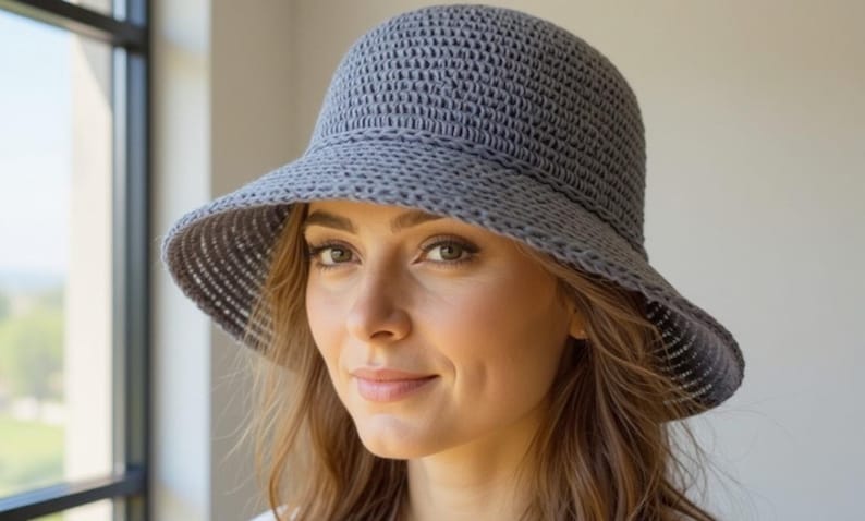 May include: A gray, woven sun hat with a wide brim. The hat has a structured crown and a slightly curved brim. The hat is made of a textured material and appears to be lightweight. The hat is designed to provide shade from the sun.