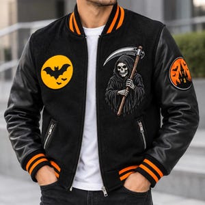 Può includere: Una giacca varsity nera con bordi a coste a righe arancioni su colletto, polsini e orlo. Il davanti presenta una toppa circolare gialla con pipistrelli neri, una grafica della morte e una toppa sulla manica che raffigura una casa stregata.