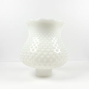 Könnte beinhalten: Weißer Lampenschirm aus Hobnail-Glas mit gerüschtem Rand. Der Schirm hat eine abgerundete Form und ist mit kleinen, erhabenen, blasenartigen Details bedeckt. Der Sockel hat eine kurze, zylindrische Form.