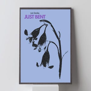 Può includere: Una stampa artistica incorniciata con un disegno floreale nero stilizzato su sfondo azzurro. Il testo "not broke, JUST BENT" è in viola e bianco. L'opera è racchiusa in una cornice di legno scuro.