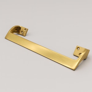 Peut inclure: Une poignée de meuble dorée avec une barre rectangulaire et des extrémités incurvées. La poignée a un design élégant et moderne avec des trous de montage à chaque extrémité. La quincaillerie est en métal et a une finition lisse et polie.