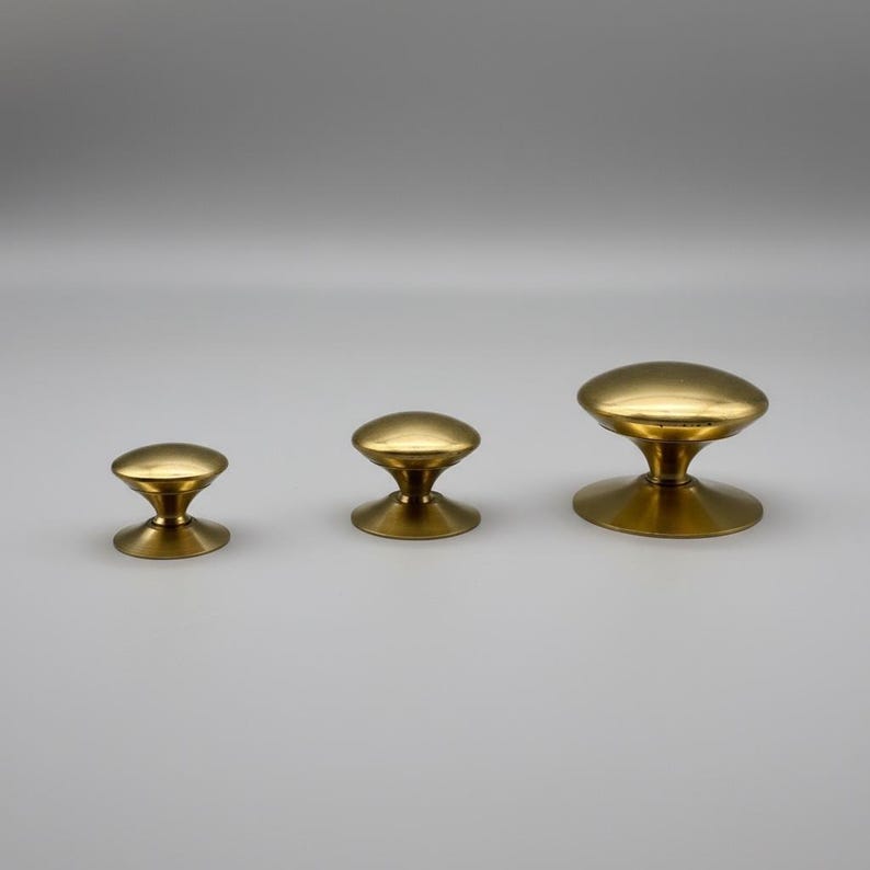 Puede incluir: Tres pomos de lat&oacute;n para armarios de diferentes tama&ntilde;os. Cada pomo tiene una parte superior redondeada y una base acampanada. Los pomos est&aacute;n dispuestos de menor a mayor, mostrando su dise&ntilde;o y acabado. Los pomos son de lat&oacute;n.