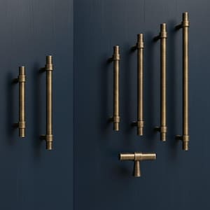 May include: A collection of antique brass cabinet pulls and handles in various sizes. The hardware is mounted on a dark blue surface. The pulls have a cylindrical design with a textured finish, and the handles are T-shaped.
