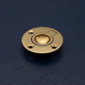 Può includere: Un tirante a filo in ottone con un design circolare. Il tirante ha un'area centrale incassata e un piccolo ritaglio rettangolare. Tre piccoli fori sono uniformemente distanziati attorno al perimetro. L'hardware è di colore oro brillante, circa 6 cm di diametro.