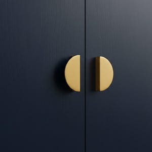 Puede incluir: Primer plano de dos tiradores de armario dorados en forma de semicírculo contra una puerta de armario azul oscuro texturizada. Los tiradores están montados en una puerta vertical con textura de vetas de madera.