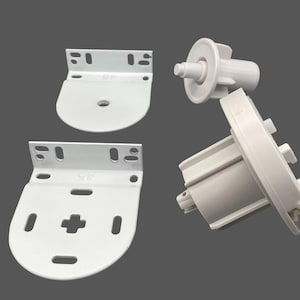 May include: White roller blind hardware components, including two mounting brackets, a roller tube, and a control mechanism. The brackets have multiple screw holes for installation. The components are made of plastic and metal.