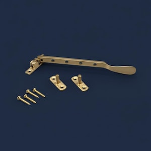May include: A brass window stay with a lever arm, two mounting plates, and several screws. The window hardware is a golden colour and is designed for installation on a window frame. The components are arranged on a dark blue background.