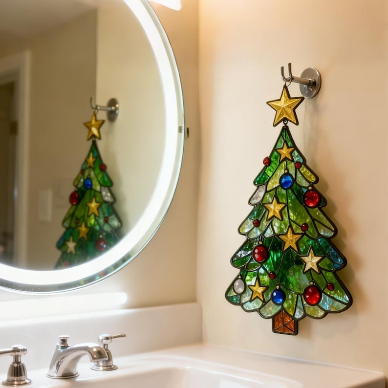 K&ouml;nnte beinhalten: Ein Weihnachtsbaumschmuck aus Buntglas mit einem goldenen Stern oben, der an einer Wand h&auml;ngt. Der Baum ist gr&uuml;n mit bunten Ornamenten und goldenen Sternen. Der Baum spiegelt sich in einem runden Spiegel.