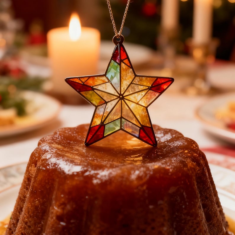 May include: A star-shaped ornament with stained glass design in red, yellow, green, and orange hues, suspended above a glazed cake. A lit candle and other festive decorations are in the background, suggesting a holiday theme.