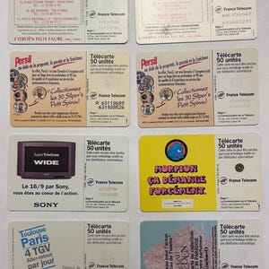 May include: A collection of vintage France Telecom phone cards, featuring various designs and text. Some cards advertise products like Citroen cars and Persil detergent. The cards are rectangular and colorful.