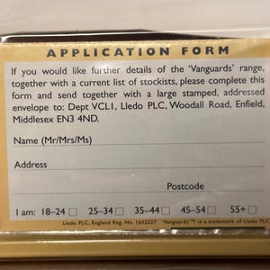 以下が含まれることがあります： 「APPLICATION FORM」のテキストが入った印刷された申請書のクローズアップ。 フォームには、名前、住所、郵便番号のフィールドと、年齢範囲のチェックボックスが含まれています。 フォームは「Vanguards」シリーズ用です。