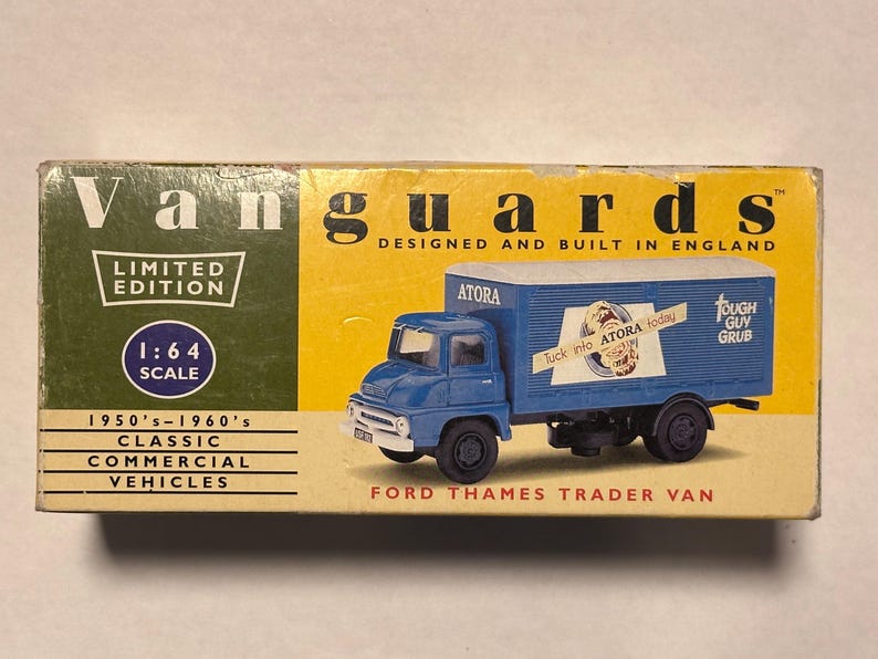 以下が含まれることがあります： 1950～1960年代の青いフォード・テムズ・トレーダー・バンの1:64スケールモデル。箱には「Vanguards」のロゴ、「Limited Edition」の文字、「Tough Guy Grub」のブランドが表示されています。
