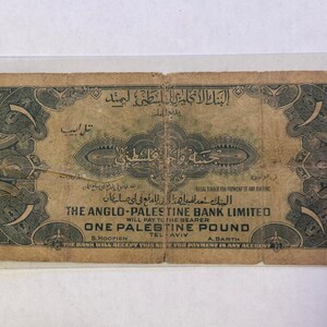 May include: An antique one Palestine pound banknote. The note is primarily tan with dark green ornate borders and text in English and Arabic. The text includes "The Anglo-Palestine Bank Limited" and "One Palestine Pound".