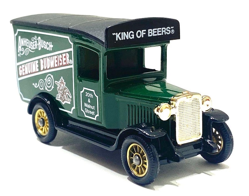 K&ouml;nnte beinhalten: Ein gr&uuml;ner und schwarzer Vintage-Spielzeug-LKW mit goldfarbenen R&auml;dern und Akzenten. Der LKW tr&auml;gt den Text "Anheuser-Busch Genuine Budweiser" an der Seite und "KING OF BEERS" auf dem Dach.