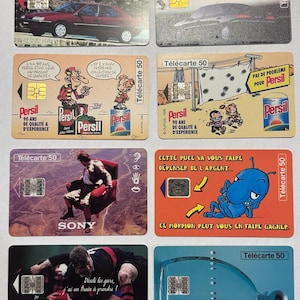 May include: A collection of vintage French T&eacute;l&eacute;carte 50 phone cards. The cards feature various designs, including cars, cartoon characters, and advertisements for Persil detergent. Some cards have the text "SONY" and "T&eacute;l&eacute;carte 50".