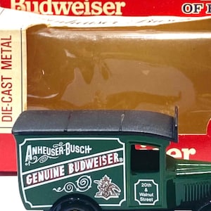 K&ouml;nnte beinhalten: Ein Spielzeug-Lieferwagen von Budweiser aus Druckgussmetall. Der gr&uuml;ne LKW tr&auml;gt die Logos von Anheuser-Busch und Budweiser in Wei&szlig;. Der Spielzeug-LKW hat goldfarbene R&auml;der und ein schwarzes Dach. Die Verpackung tr&auml;gt die Aufschrift "Adult Collectable".