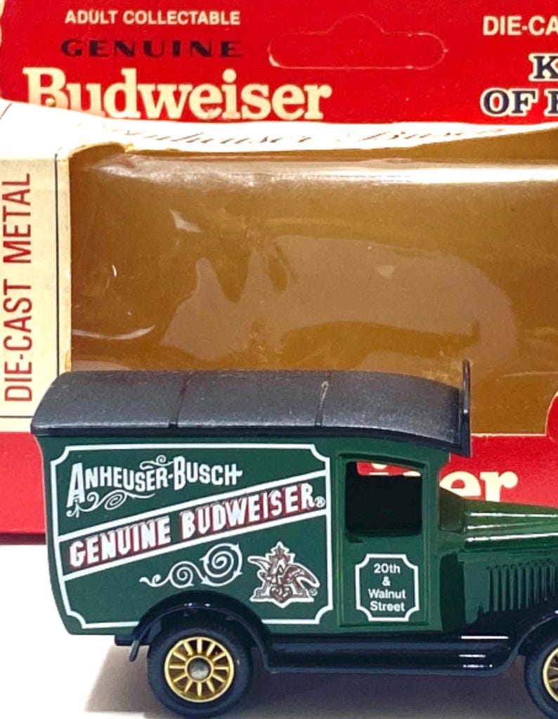 K&ouml;nnte beinhalten: Ein Spielzeug-Lieferwagen von Budweiser aus Druckgussmetall. Der gr&uuml;ne LKW tr&auml;gt die Logos von Anheuser-Busch und Budweiser in Wei&szlig;. Der Spielzeug-LKW hat goldfarbene R&auml;der und ein schwarzes Dach. Die Verpackung tr&auml;gt die Aufschrift "Adult Collectable".